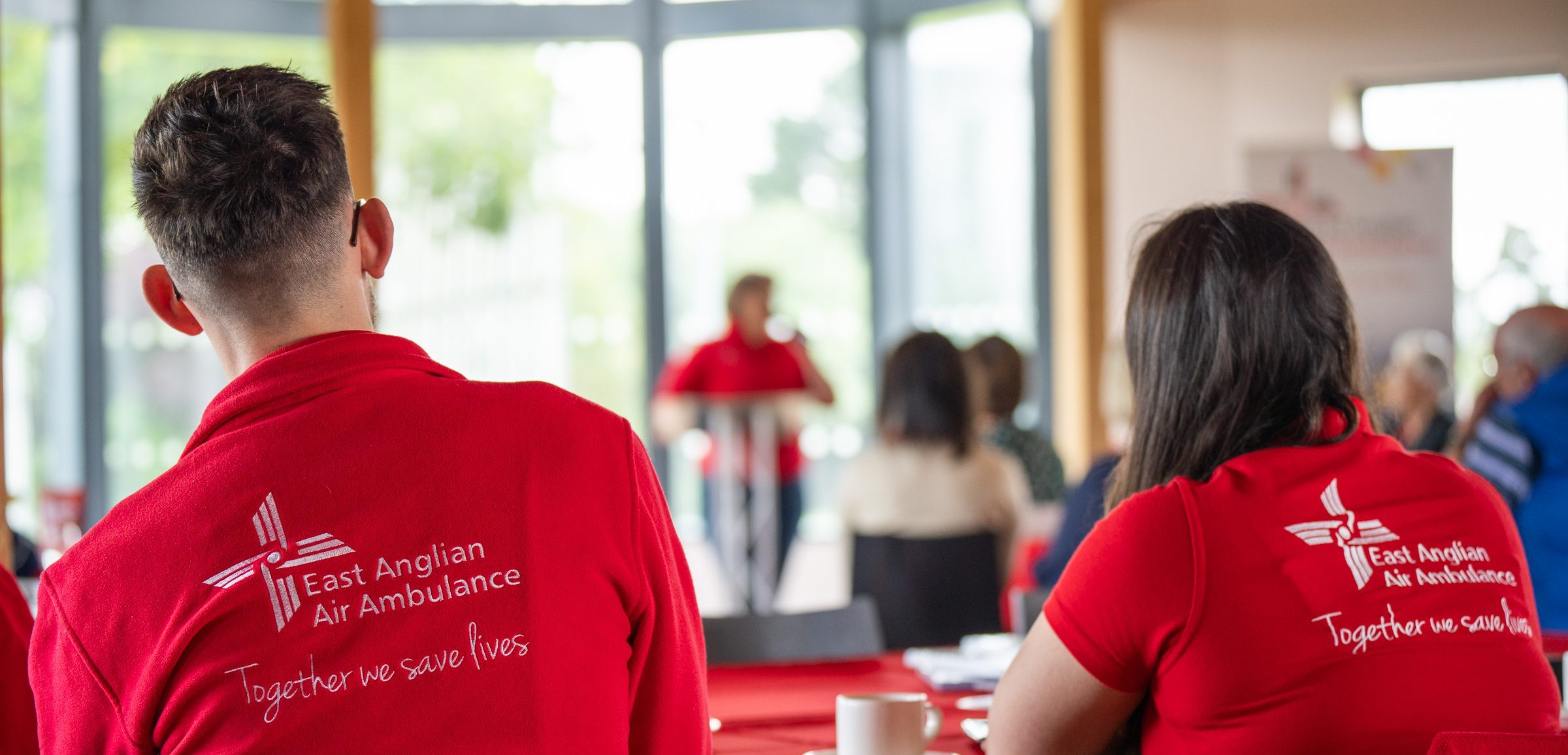 The back of two EAAA volunteers wearing branded red clothing