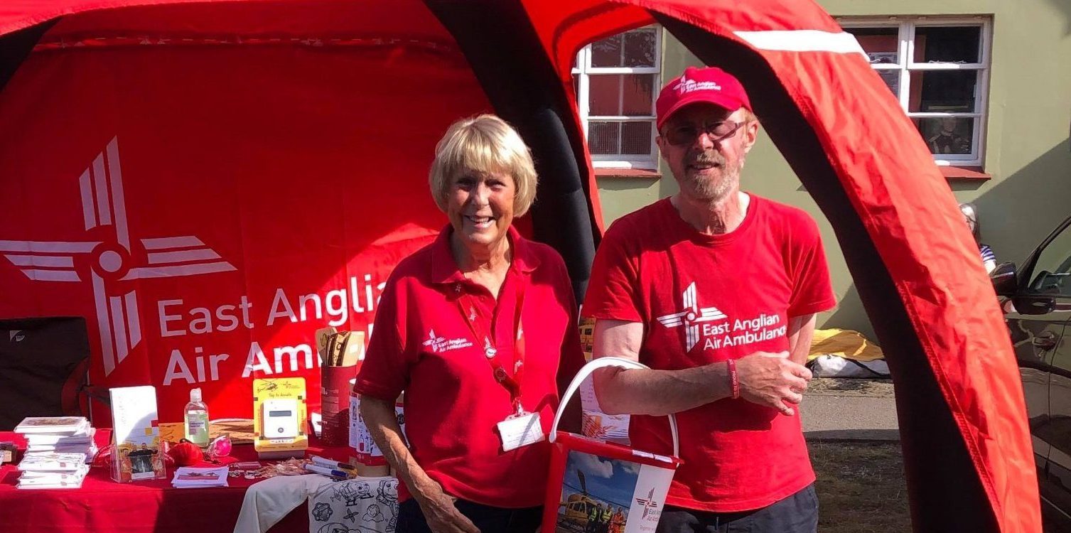 Two EAAA Volunteers standing in front of branded stand, holding collection buckets