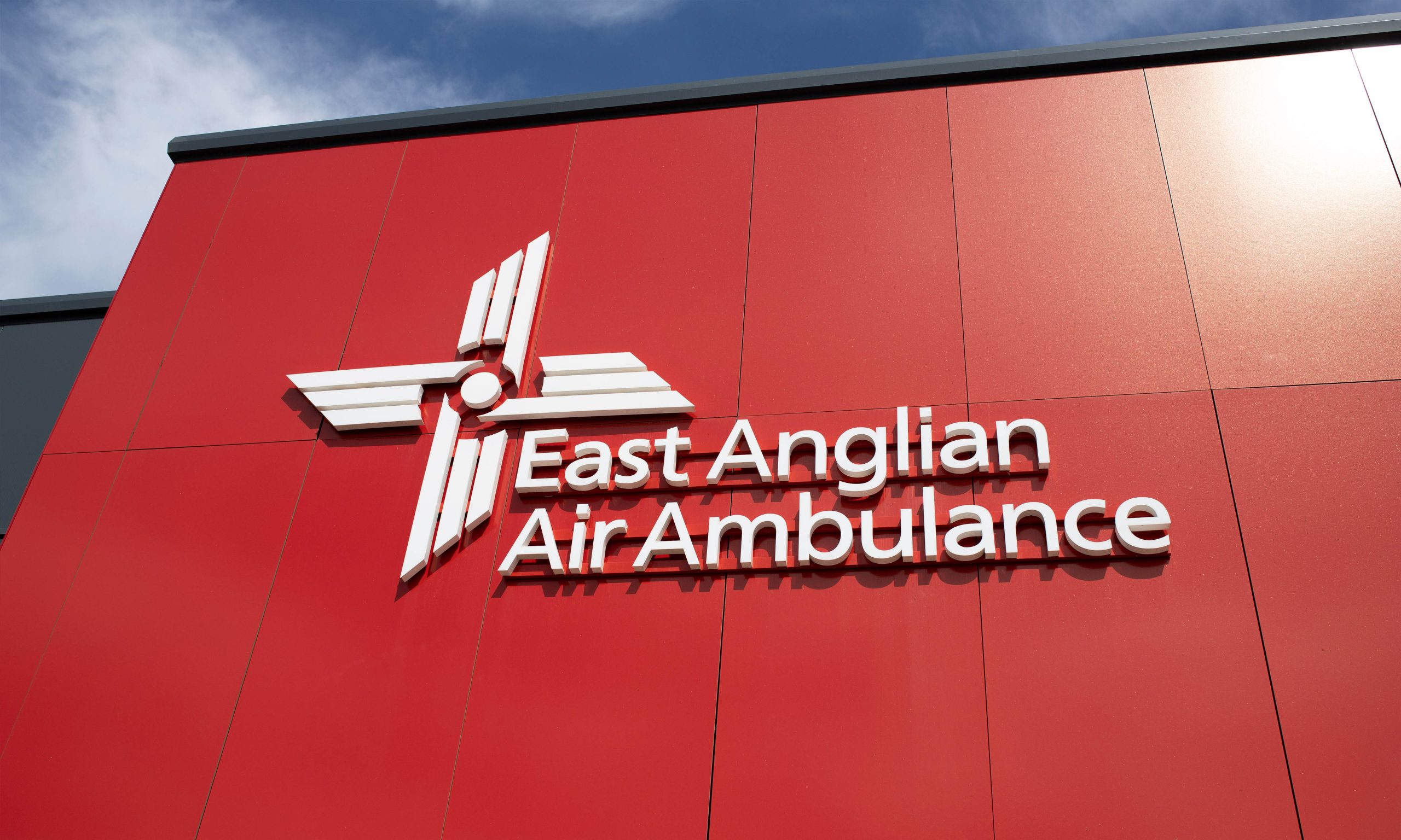 The front of Helimed house with a red wall and white EAAA branding