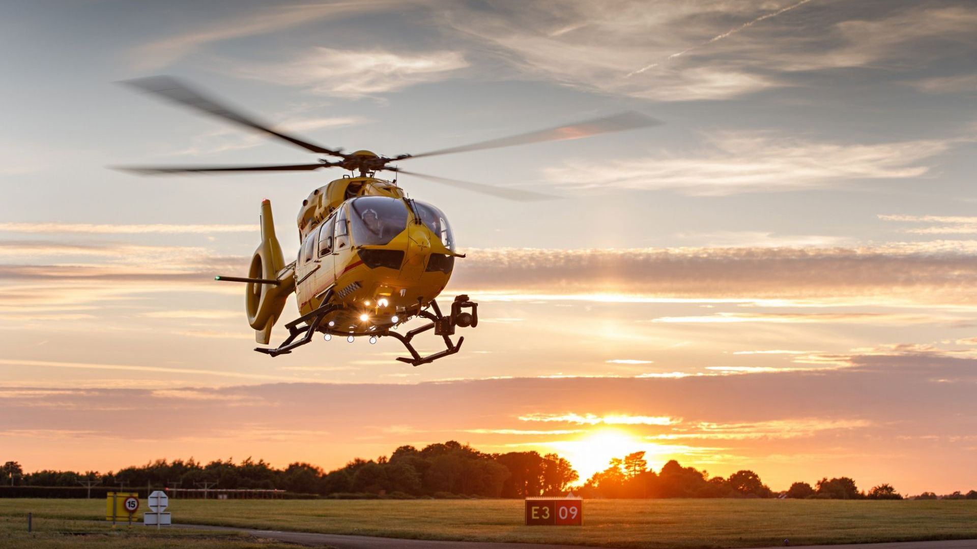 East Anglian Air Ambulance helicopter landing at sunset