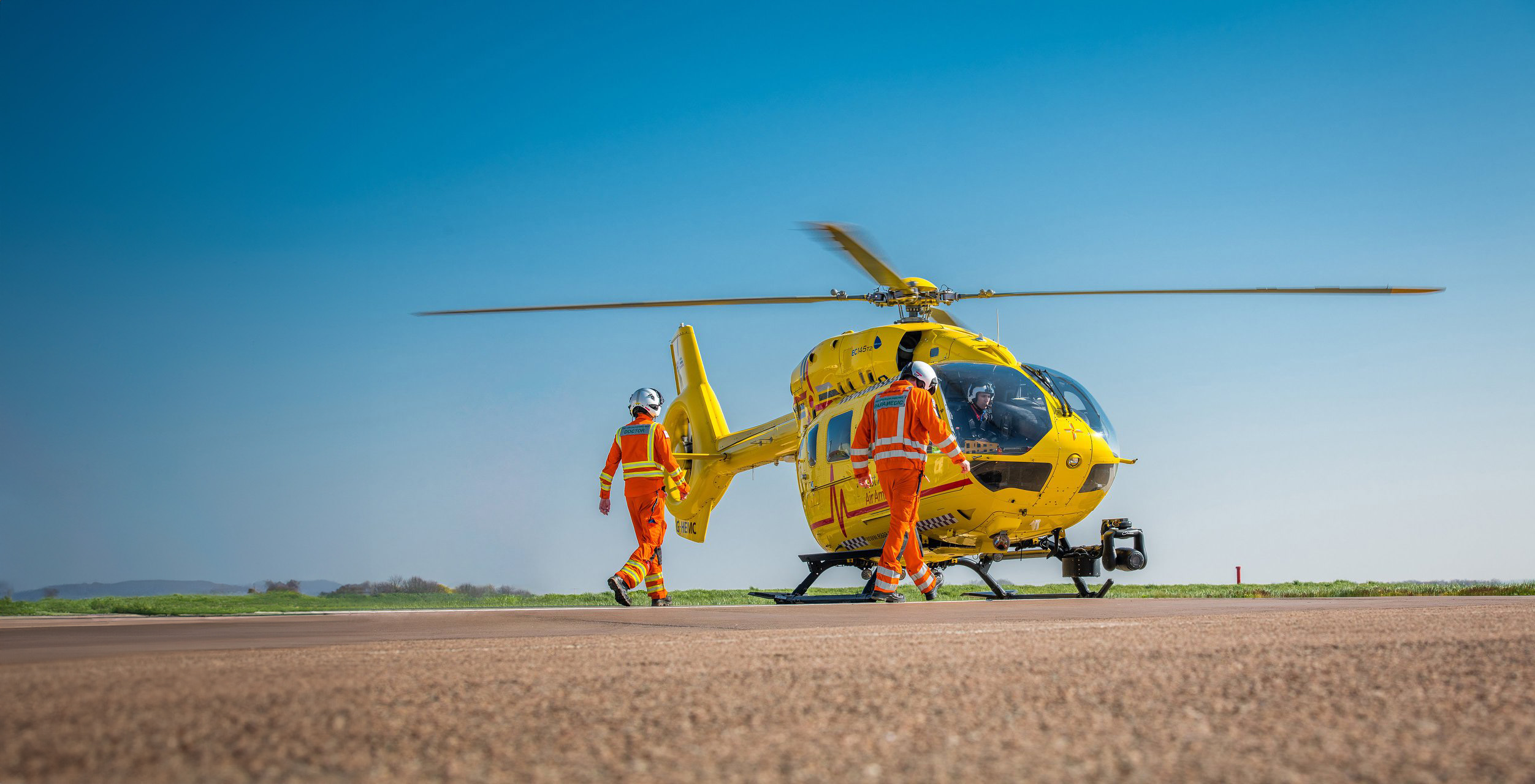 Crew walking to Anglia Two helicopter in sunshine