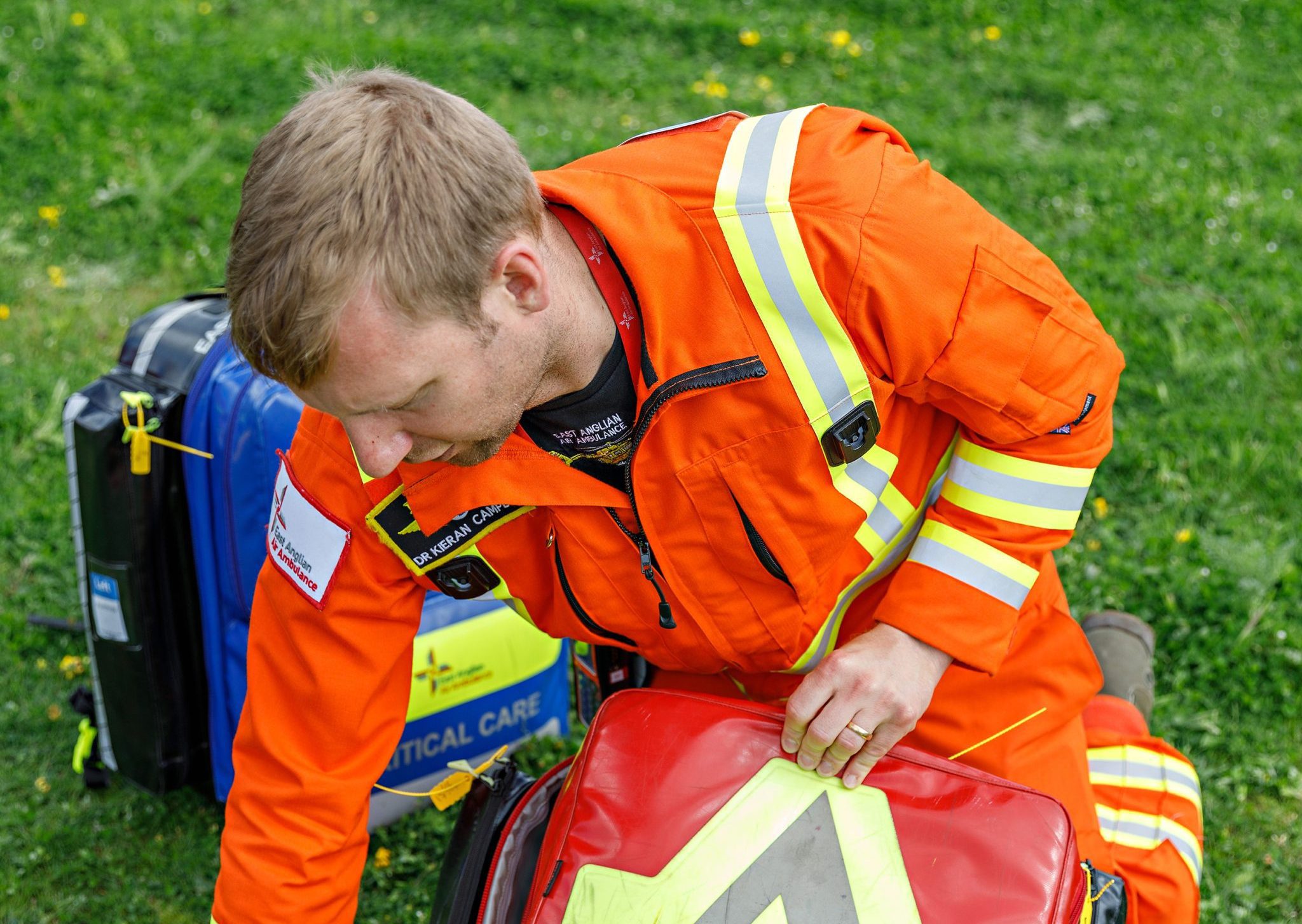 Doctor opening red kit bag on grass