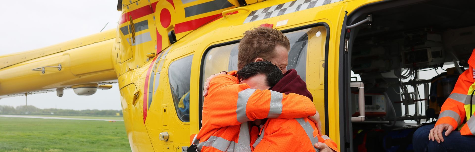 2 members of the EAAA crew hugging in front of helicopter