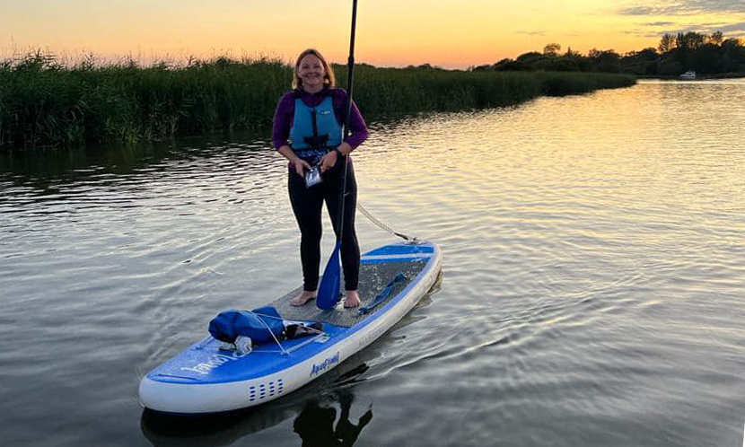 Women standing on a paddleboard at sunset